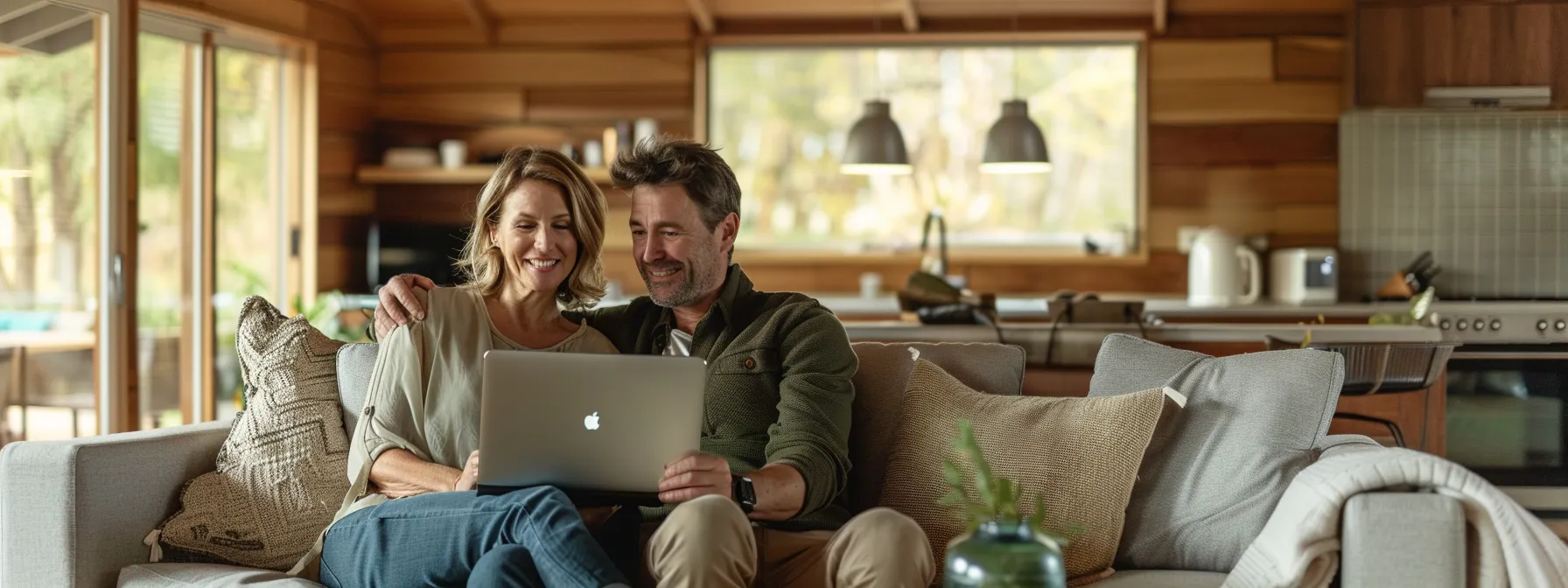 A cozy rural Australian home interior featuring a Caucasian couple in their mid-30s, sitting close together on a comfortable sofa. The man has short, light brown hair, and the woman has shoulder-length blonde hair. They are both smiling and engaged in a relaxed conversation while using a laptop and a tablet. The living room is warmly lit with natural light, wooden furniture, and soft earthy tones, creating an inviting and homely atmosphere. The image conveys trust, security, and optimism as the couple discusses their financial future, reflecting the benefits of debt consolidation in a rural setting.